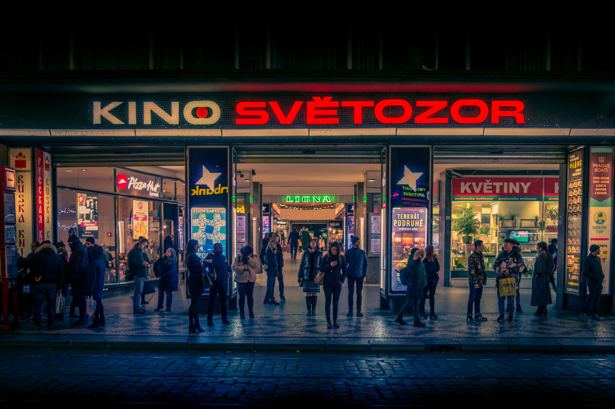 Façade éclairée du cinéma Kino Světozor à Prague, de nuit, avec des passants devant l’entrée