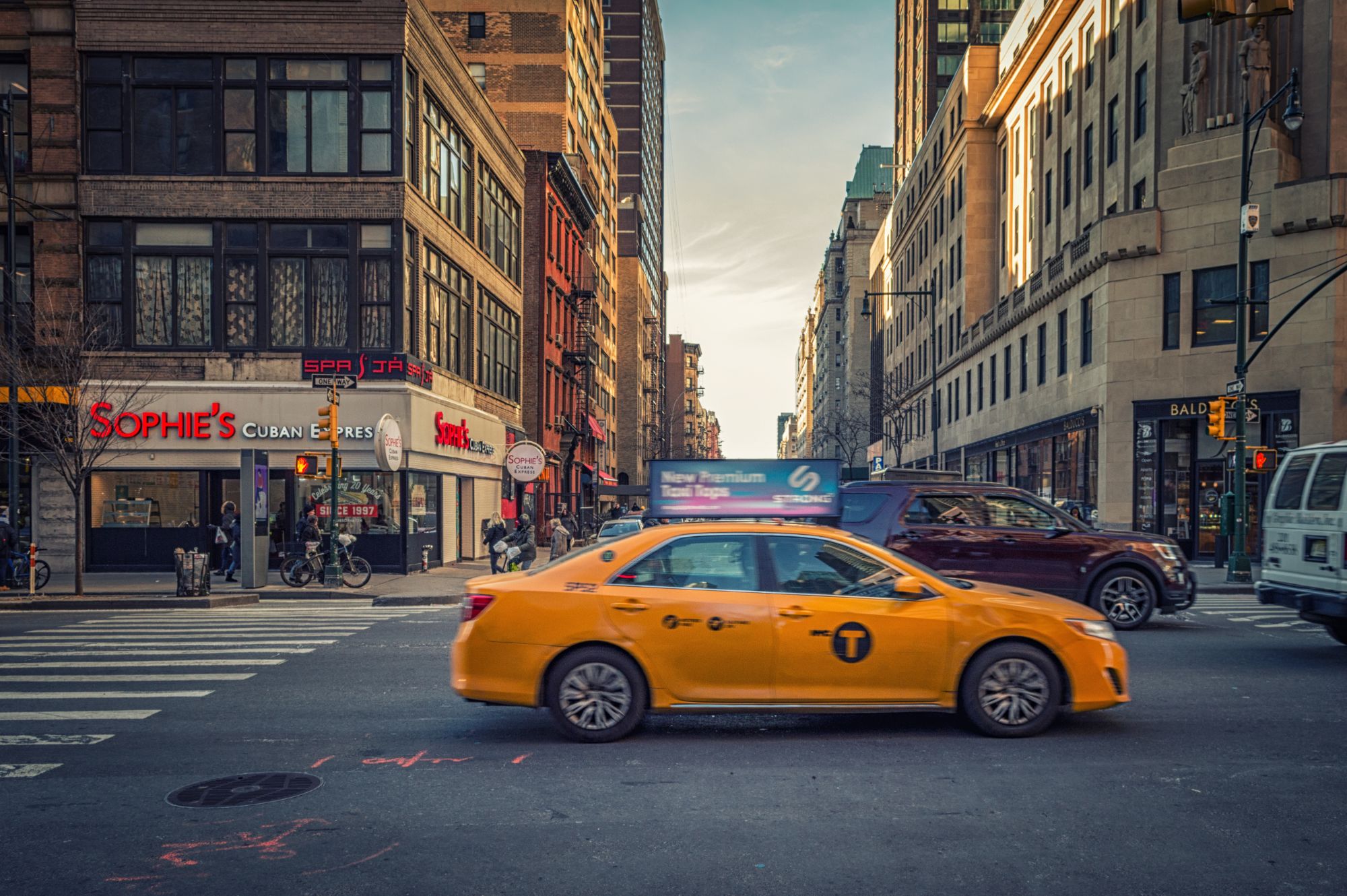 Taxi jaune dans une rue de New York bordée d’immeubles en brique